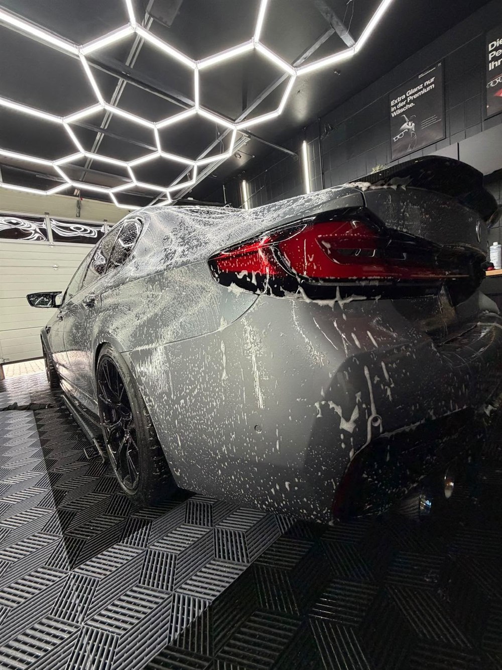 BMW M5 Competition in Grau matt, seitliche Heckansicht beim Einschäumen im Studio in Peine