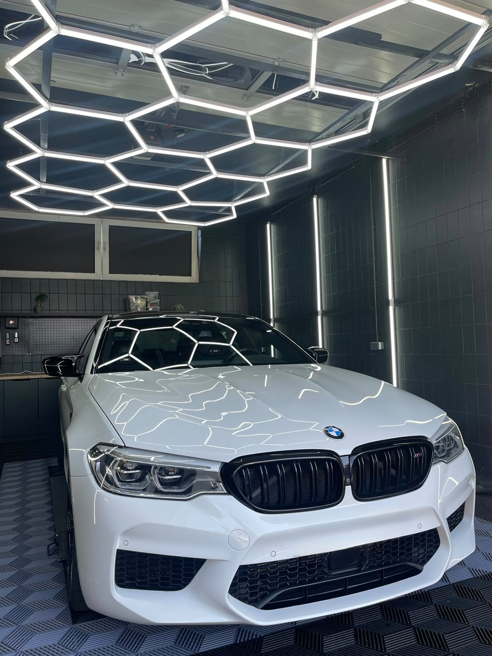 Weißer BMW M5 Competition, frontale Ansicht mit Lackreflexionen im Studio in Peine
